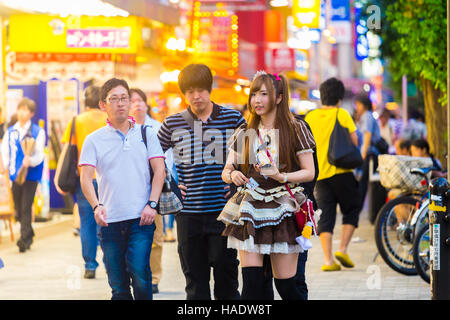 Jeune japonaise en costume de bonne français d'attirer une clientèle masculine sur le trottoir pour entrer maid café restaurant japonais Banque D'Images