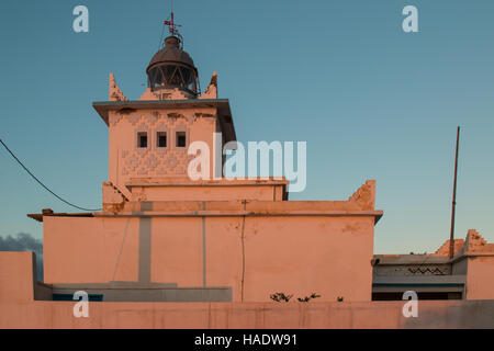 Les murs de couleur phare dans une couleur orange par le coucher du soleil la lumière. Début de soirée bleu ciel. Tour avec une lumière, toujours éteint. Sidi Ifni, Maroc. Banque D'Images