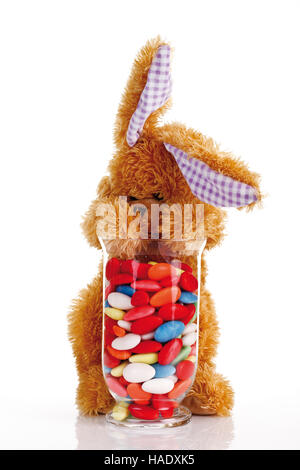 Doudou lapin de Pâques avec les oeufs de pâques bonbons dans un verre Banque D'Images
