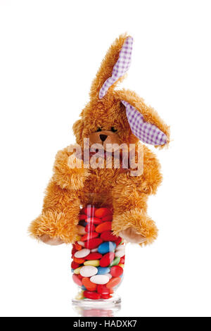 Doudou lapin de Pâques avec les oeufs de pâques bonbons dans un verre Banque D'Images