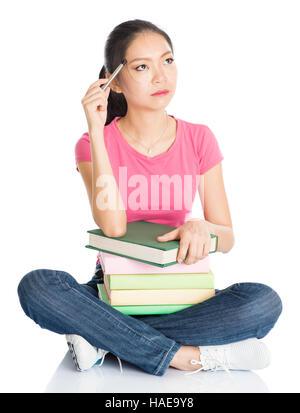 Corps plein Young Asian female student in pink shirt avec les manuels scolaires, assis sur le plancher, pleine longueur isolé sur fond blanc. Banque D'Images