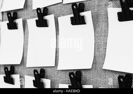 Affichage avec clips holding blank notes papier carré près. Vue sous un angle en noir et blanc Banque D'Images