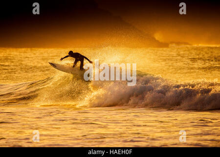 Au cours de surf un spectaculaire coucher du soleil doré à dans Fistral Newquay, Cornwall. UK. Banque D'Images