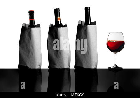 Masquer les étiquettes sur les sacs de bouteilles de vin comme ils se tiennent à côté d'un verre de vin lors d'une dégustation aveugle. Banque D'Images