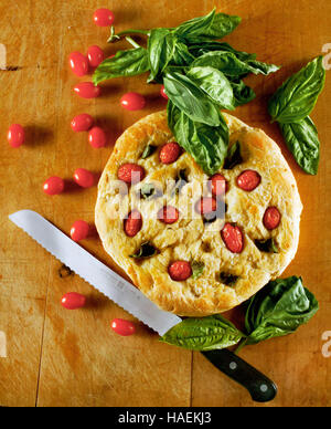 Focaccia avec tomates cerises et basilic est sorti du four et prêt à trancher. Banque D'Images