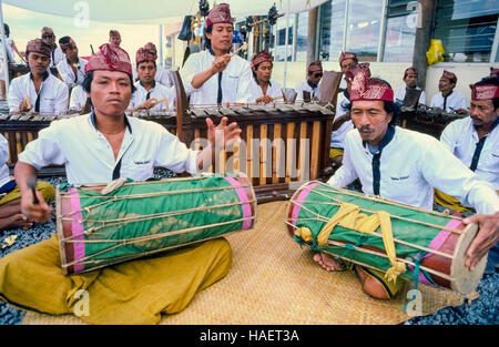 Un ensemble musical traditionnel indonésien appelé gamelan est effectué sur les instruments à percussion pour les visiteurs de l'île de Bali en Indonésie en Asie du sud-est. Vu voici deux tambours dirigés par kendhangs kendangs appelé (ou), et qui sont à l'écoute les métallophones des barres de métal frappé avec des maillets en bois. Banque D'Images