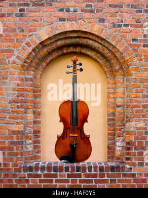 Le magnifique violon en la fenêtre aveugle dans le vieux mur de brique Banque D'Images