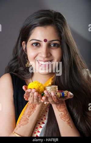 Une fille souriante et tenant une lampe à huile traditionnelle Diwali diya avec fleur offrande religieuse et souriant Mumbai Inde Banque D'Images