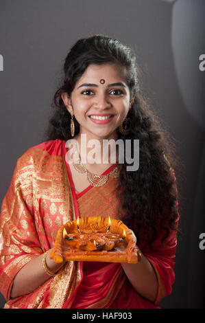 Une fille souriante et tenant une lampe à huile traditionnelle Diwali diya Mumbai maharashtra Inde Banque D'Images