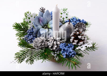 Centre de table de Noël avec une bougie et poinsettias en soie bleue. Fond de Noël avec des pommes de pin décorées. Banque D'Images