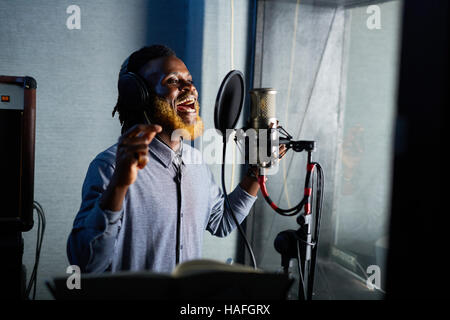 Jeune chanteur chantant en studio d'enregistrement à Mike Banque D'Images