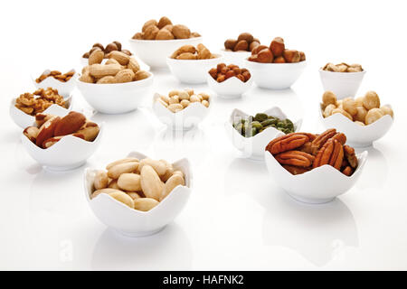 Un assortiment de noix et amandes dans des bols en céramique, pacanes, noix, noisettes, noix de macadamia, cacahuètes, amandes, pistaches Banque D'Images