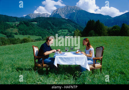 Couple eating at a table set dans un pré en face de la Grosse Montagne Phuergas, Haute Autriche, Europe Banque D'Images