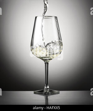 Verser le vin blanc dans un verre d'en haut, vue latérale sur un fond gris avec vignette d'un concept de viticulture Banque D'Images