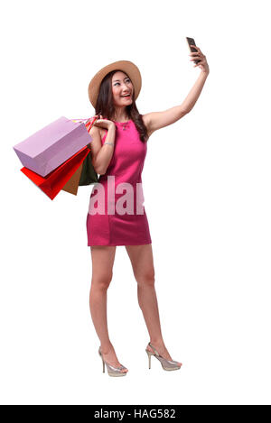 Beautiful asian girl holding shopping bags et en tenant avec selfies cellphone isolated on white background studio Banque D'Images