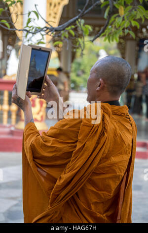 Un moine bouddhiste en utilisant un ipad pour photographier le Kuthodew pagode à Mandalay, Myanmar (Birmanie). Banque D'Images