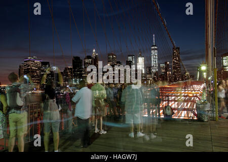 Les touristes sur le pont de Brooklyn, admirer le centre-ville de Manhattan au coucher du soleil (longue exposition), New York, United States. Banque D'Images