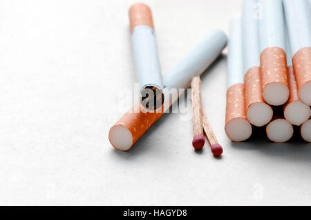 Les cigarettes et les match sur du papier blanc background.Shallow DOF. Banque D'Images