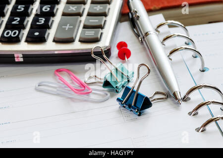 Calculatrice, trombones et stylo sur carnet de notes vierge Banque D'Images