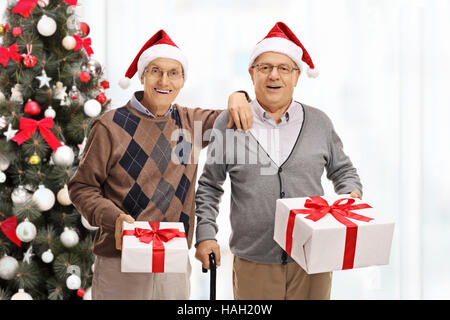 Les personnes âgées gaies avec présente devant un arbre de Noël isolé sur fond blanc Banque D'Images