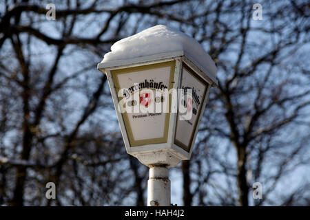 Lampe lanterne couverte de neige avec publicité de bière Herrenhäuser. Dornröschen Beer Garden, Hanovre, Basse-Saxe, Allemagne. Banque D'Images