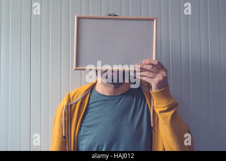 Méconnaissable homme posant avec cadre photo Blanc sur son visage comme copy space Banque D'Images