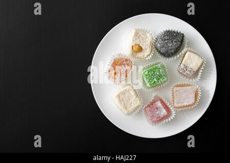 Plaque blanche avec bonbons colorés sur tableau noir Banque D'Images
