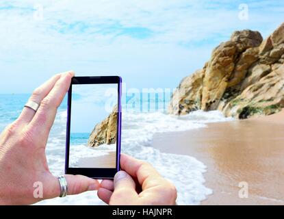 Vue sur l'écran du téléphone lors de la prise d'une photo de plage de Calella Costa Brava, Espagne. Maintenant le téléphone mobile dans les mains et prendre une phot Banque D'Images