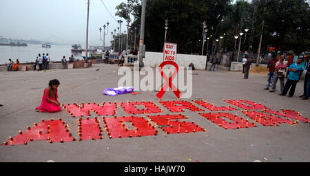 Kolkata, Inde. 06Th Dec 2016. Militant et enfants de dessiner le symbole DE LUTTE CONTRE LE SIDA et les lampes s'allume pendant le programme de la campagne. Dessiner le symbole militant contre le sida et les lumières diya ou aussi lampe lanterne ciel libération pendant une campagne de sensibilisation sur la Journée mondiale de lutte contre le sida sur la banque du fleuve Ganga. La Journée mondiale du sida célébrée chaque année le 01 décembre pour sensibiliser sur le VIH/SIDA et de démontrer la solidarité internationale face à la pandémie. Credit : Saikat Paul/Pacific Press/Alamy Live News Banque D'Images