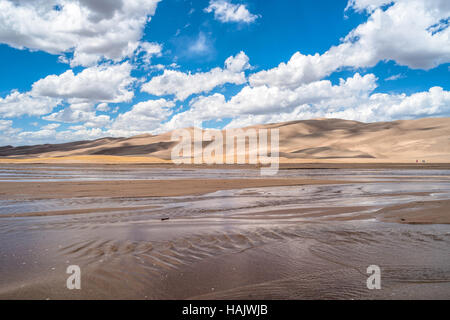 Au printemps Great Sand Dunes - nuages blancs, le ciel bleu, en passant sur des dunes de sable et de Medano Creek qui coule doucement. Banque D'Images