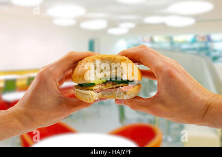 Mains tiennent un hamburger dans un restaurant fast food Banque D'Images