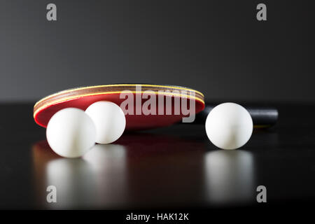 Raquette de tennis de table et boules sur table sombre Banque D'Images