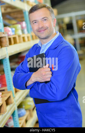 Man in warehouse holding clipboard pour sa poitrine Banque D'Images