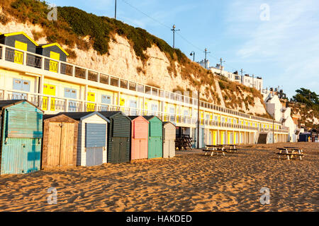 L'Angleterre, Broadstairs. À l'aube. Vue le long des cabines de plage avec terrasse de même au-dessus, sur la plage vide dans l'heure d'or lever tôt le matin la lumière. Banque D'Images