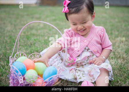 Portrait of Girl wearing Pink et assis sur l'herbe avec Easter basket in Backyard Banque D'Images