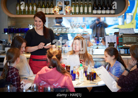 Pizza Express restaurant cuisine italienne serveuse intérieur waiter serving clients heureux chers enfants prenant note pad book Manchester Oxford Banque D'Images