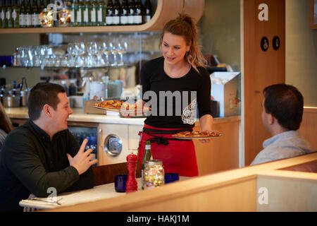 Pizza Express restaurant cuisine italienne serveuse intérieur waiter serving clients heureux chers enfants prenant note pad book Manchester Oxford Banque D'Images