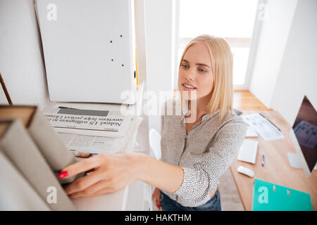 Close up portrait of a young Pretty woman taking business book from bookshelf Banque D'Images