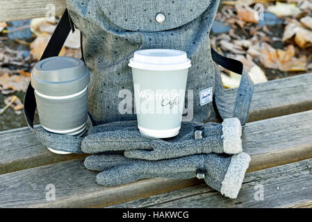 Waitrose emporter jetables avec la tasse de café tasse en plastique réutilisables sur gris Gants polaire en face de sac à dos urbain intelligent. Banque D'Images