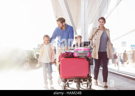 Famille avec le chariot à bagages de l'aéroport à l'extérieur de marche Banque D'Images