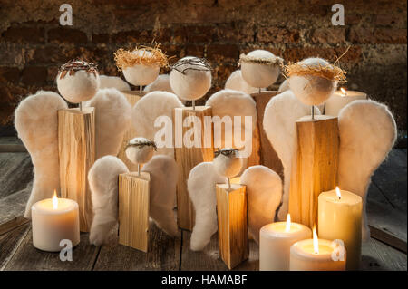 Décoration de Noël, groupe des anges à la main sur la vieille table en bois, allume les bougies blanches, en face de mur de brique Banque D'Images