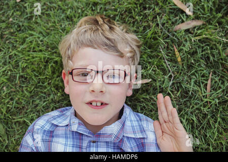 Heureux petit garçon portant des lunettes portant sur l'herbe Banque D'Images