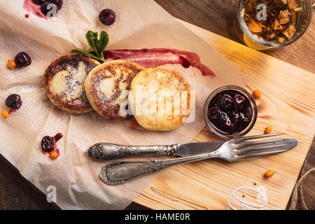 Concept : Les menus de restaurant, d'une saine alimentation, faits maison, gourmands, la gourmandise. Crêpes au fromage servi avec la sauce aux cerises sur le papier avec des ingrédients sur vintag Banque D'Images