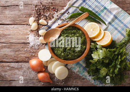 Chimichurri sauce épicée verte et les ingrédients sur la table horizontale vue du dessus. Banque D'Images