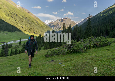 Un blanc mountaineer homme marche dans une vallée avec un fond de montagne Banque D'Images