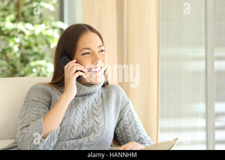 Femme parlant au téléphone une ligne de terre assis sur un canapé dans la salle de séjour à la maison Banque D'Images