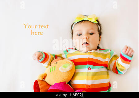 Visage de bébé enfant mignon surpris fille en pyjamas de couleur avec un arc sur sa tête, making bouche d'expression. Copy space Banque D'Images