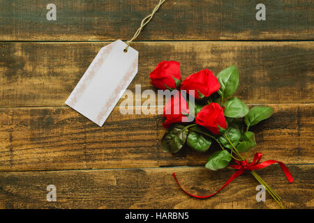 Modèle d'étiquette à côté d'un bouquet de roses rouges sur un fond de bois rustique Banque D'Images