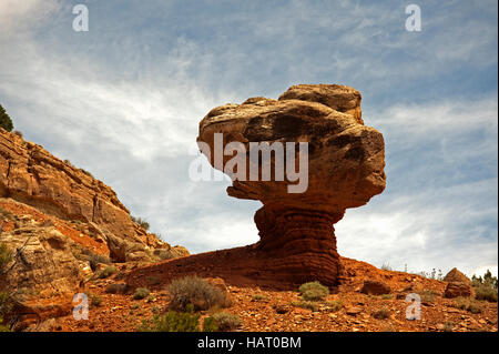 Rocher de grès d'équilibrage sur pilier de grès dans le parc national de Capital Reef, avec Ciel et nuages épars cathedral Valley. Banque D'Images