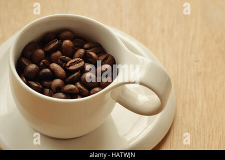 Grains de café dans une tasse sur fond de bois Banque D'Images